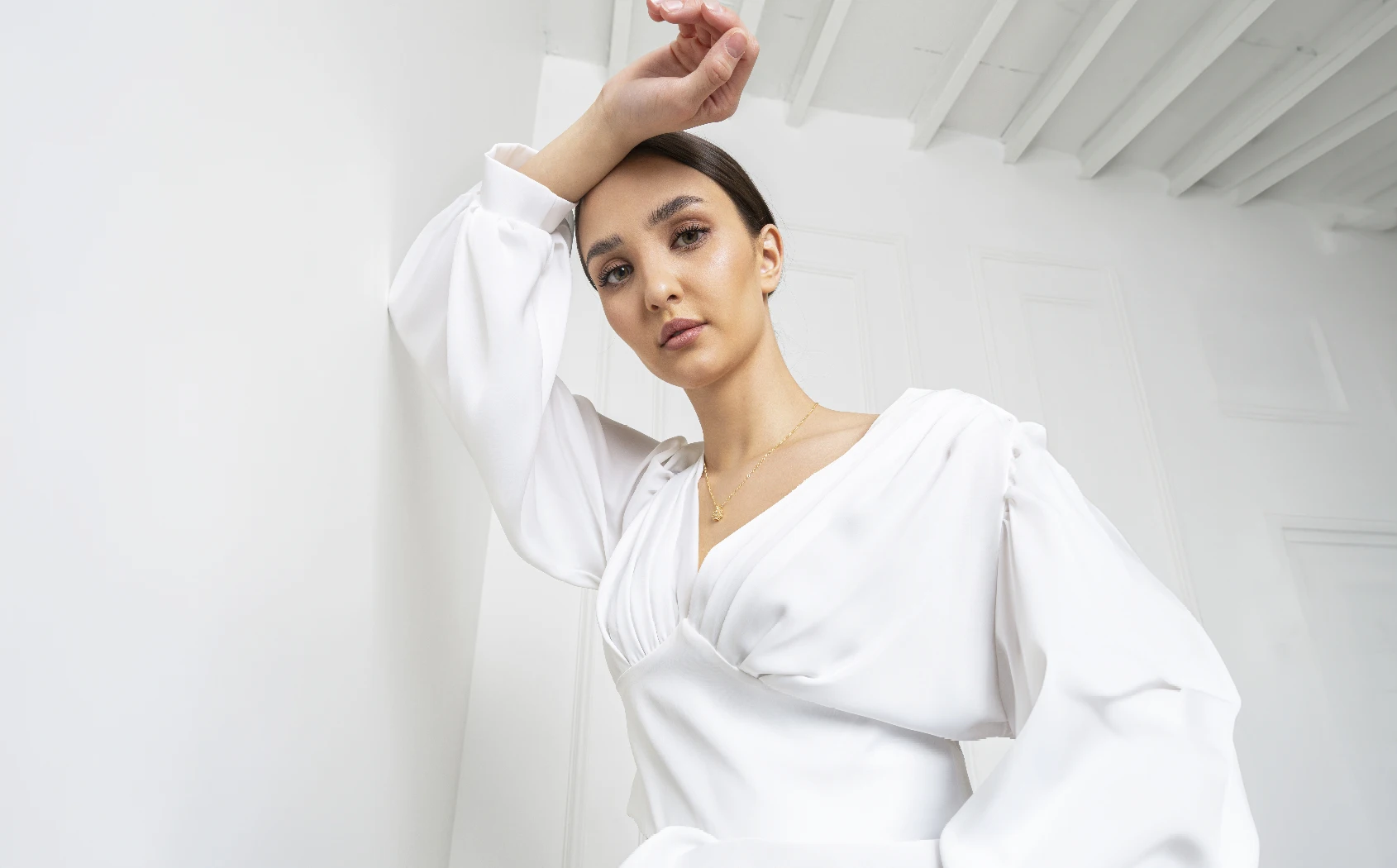 dark haired woman in white blouse leaning against a white wall | Houston Beautiful Body in Houston, TX